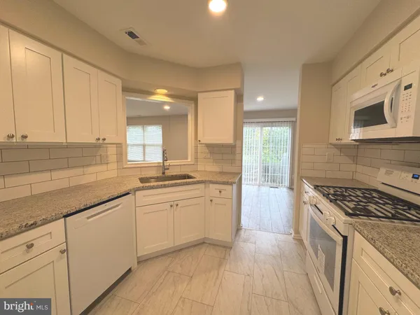 a kitchen with granite countertop a sink stove and cabinets