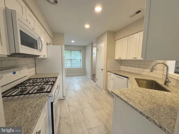 a kitchen with granite countertop a sink stove and cabinets