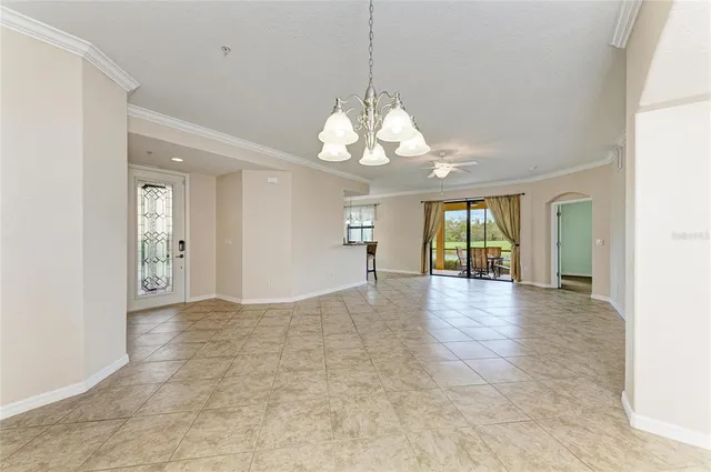 a view of an empty room with window and chandelier fan