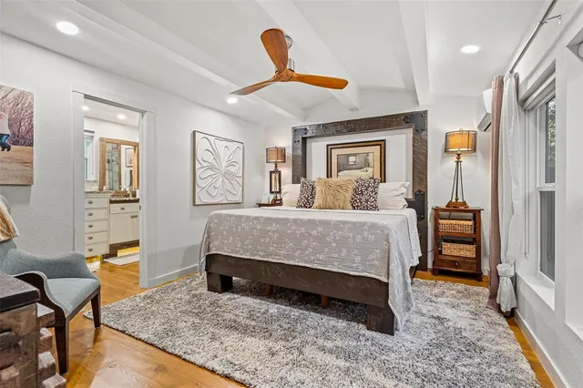 a bedroom with a bed a dresser and potted plant with the wooden floor