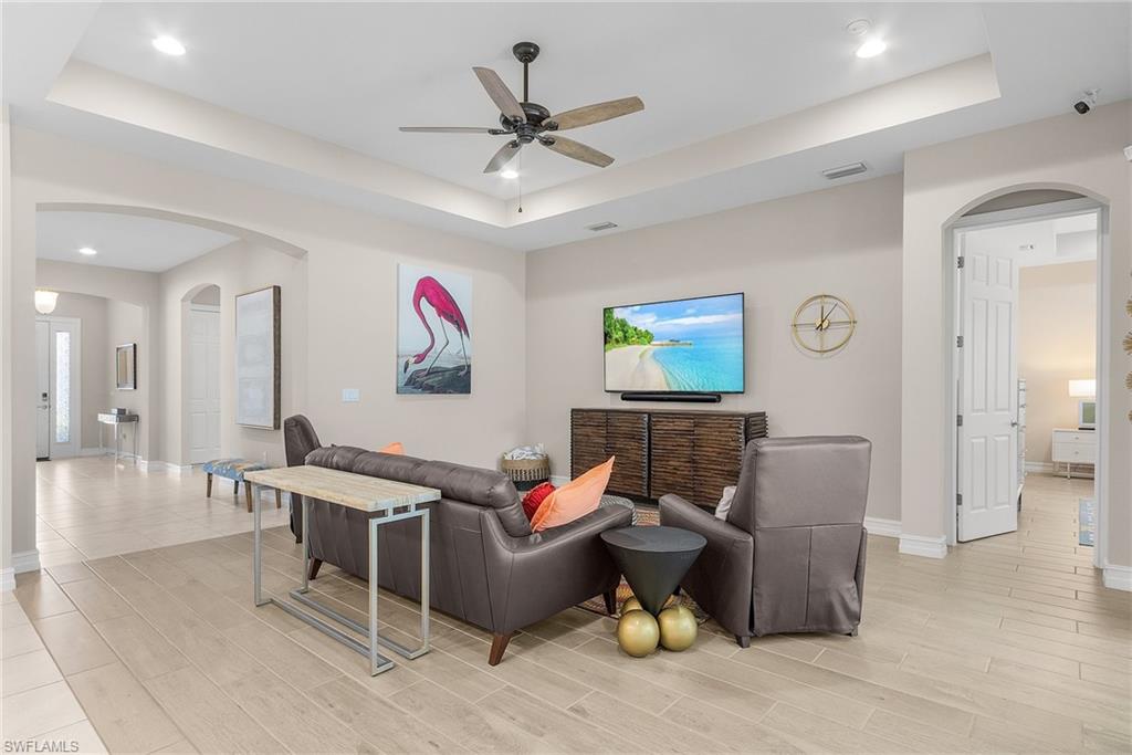 14539 Kelson Circle Naples, FL 34114 - Photo 11 of 37 Living room featuring arched walkways, a raised ceiling, a ceiling fan, recessed lighting, and wood finish floors