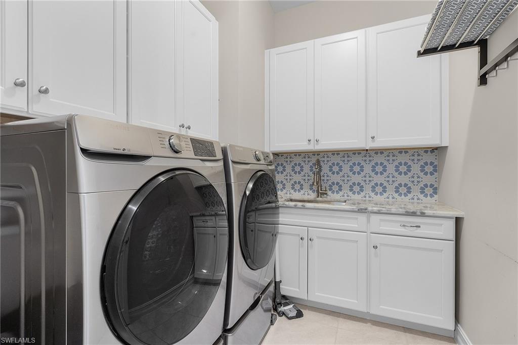 14539 Kelson Circle Naples, FL 34114 - Photo 27 of 37 First floor laundry area with washer and dryer, light tile patterned floors, and cabinet space