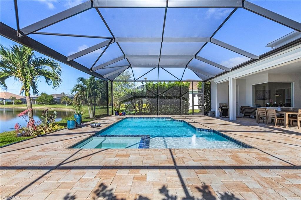 14539 Kelson Circle Naples, FL 34114 - Photo 31 of 37 View of swimming pool and hot tub, with a patio area, a pool with connected hot tub, a sunroom, glass enclosure, and a water view