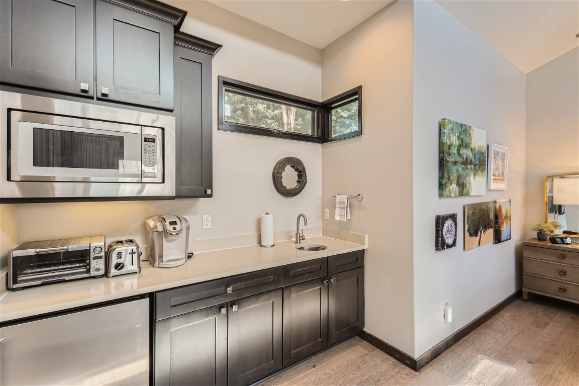 2113 Barbaro Way, Unit 14 Spicewood, TX 78669 - Photo 4 of 18 Kitchen featuring light wood-type flooring, stainless steel microwave, and light countertops