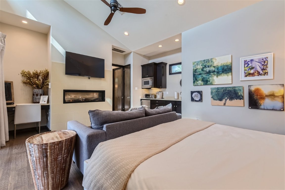 2113 Barbaro Way, Unit 14 Spicewood, TX 78669 - Photo 6 of 18 Bedroom with lofted ceiling, recessed lighting, a glass covered fireplace, ceiling fan, and wood finished floors