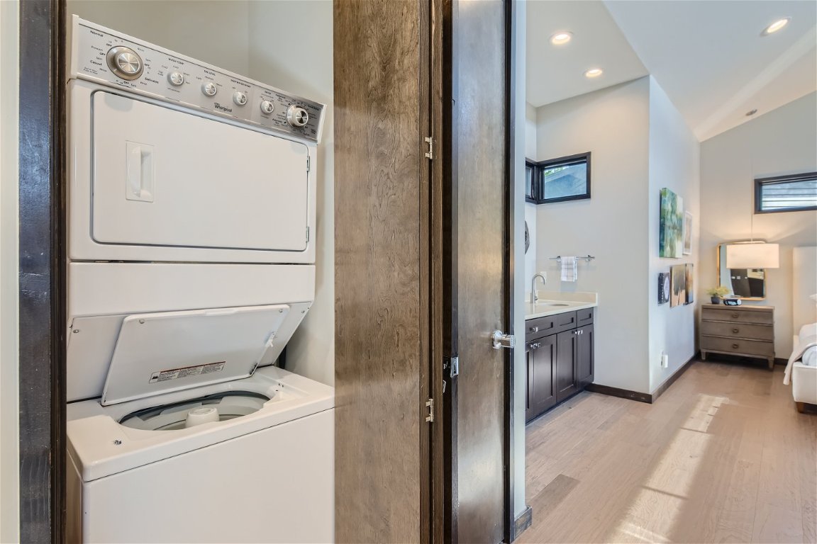 2113 Barbaro Way, Unit 14 Spicewood, TX 78669 - Photo 9 of 18 Clothes washing area featuring stacked washer / drying machine, recessed lighting, light wood-style floors, a sink, and laundry area