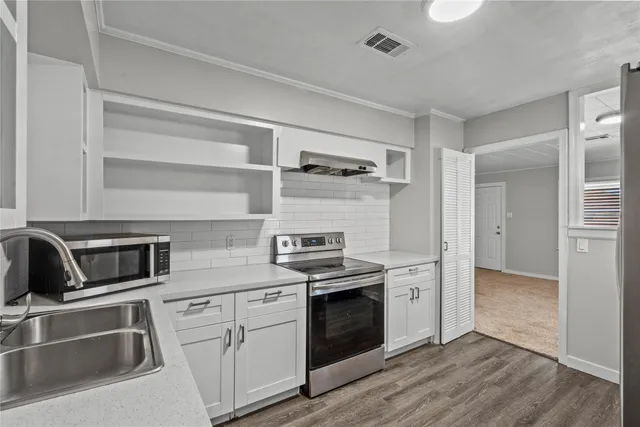 a kitchen with cabinets stainless steel appliances and wooden floor