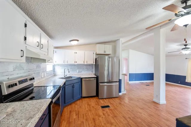 a kitchen with stainless steel appliances granite countertop a refrigerator a stove and a sink