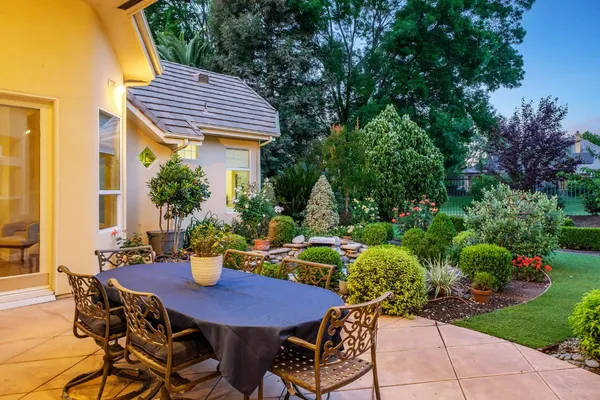 a patio with table and chairs and potted plants