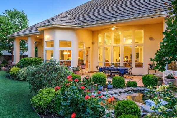 a front view of house and yard with beautiful flowers and green space