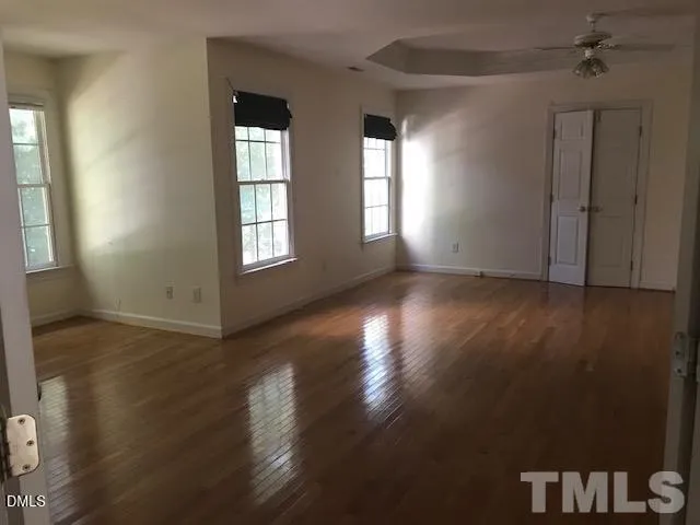 a view of an empty room with wooden floor and a window