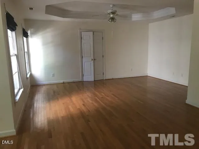 a view of an empty room with wooden floor and a window