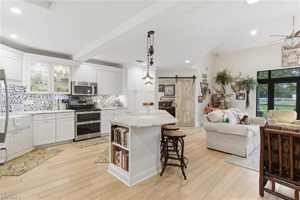 3800 Staley Road Fort Myers, FL 33905 - Photo 28 of 50 a kitchen with stainless steel appliances kitchen island granite countertop a stove a sink a refrigerator and white cabinets with wooden floor