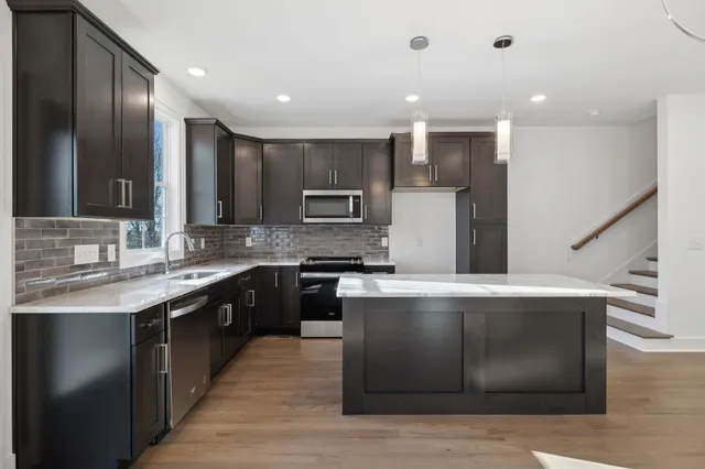 a large kitchen with stainless steel appliances granite countertop a large counter top a sink and a stove