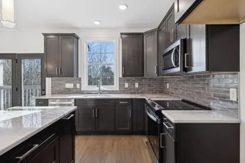 a kitchen with stainless steel appliances granite countertop a sink stove and cabinets