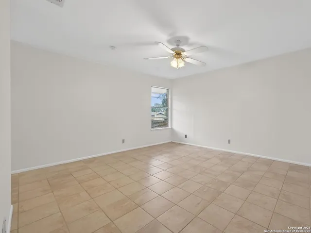 an empty room with a window and a ceiling fan