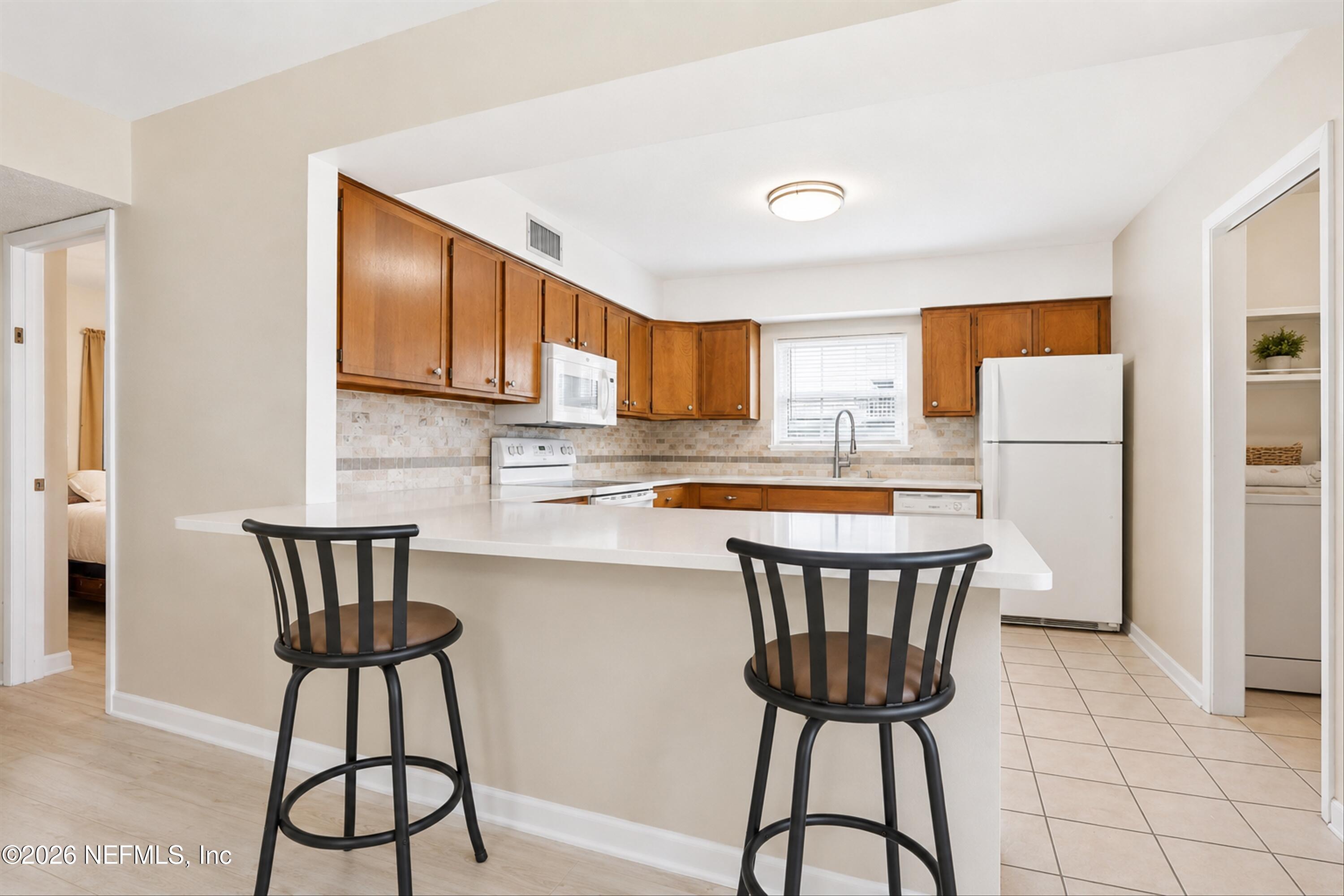 124 Hopkins Street Neptune Beach, FL 32266 - Photo 20 of 44 a kitchen with a dining table chairs and refrigerator