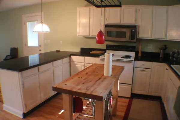 a kitchen with granite countertop a sink a stove a microwave and cabinets