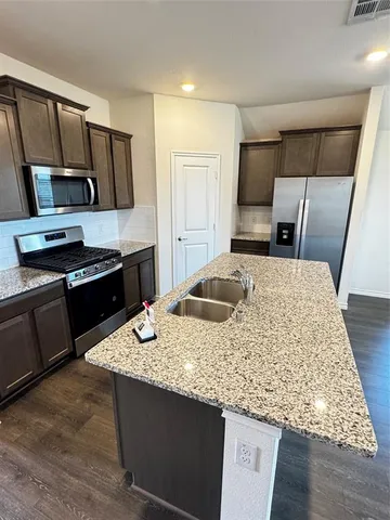 a kitchen with kitchen island granite countertop a sink stove and refrigerator