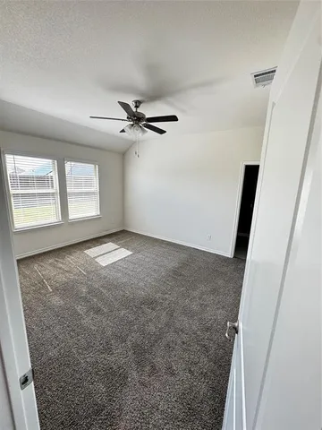 an empty room with windows and fan