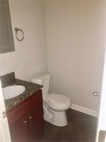 a bathroom with a granite countertop toilet and a sink