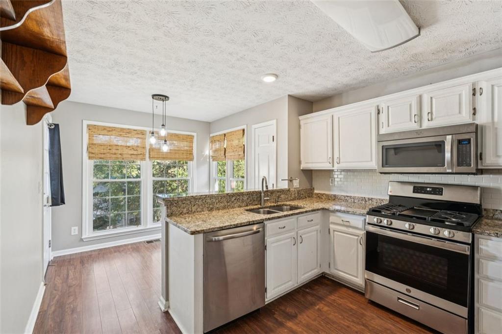 2470 Jakin Way Suwanee, GA 30024 - Photo 15 of 64 a kitchen with stainless steel appliances granite countertop a stove a sink and a microwave