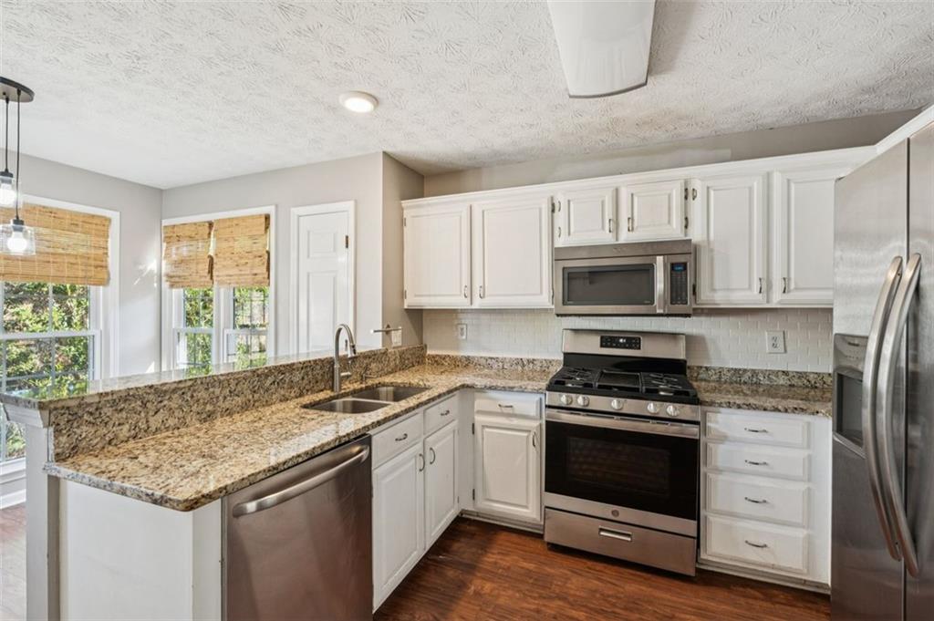 2470 Jakin Way Suwanee, GA 30024 - Photo 16 of 64 a kitchen with granite countertop white cabinets and white appliances