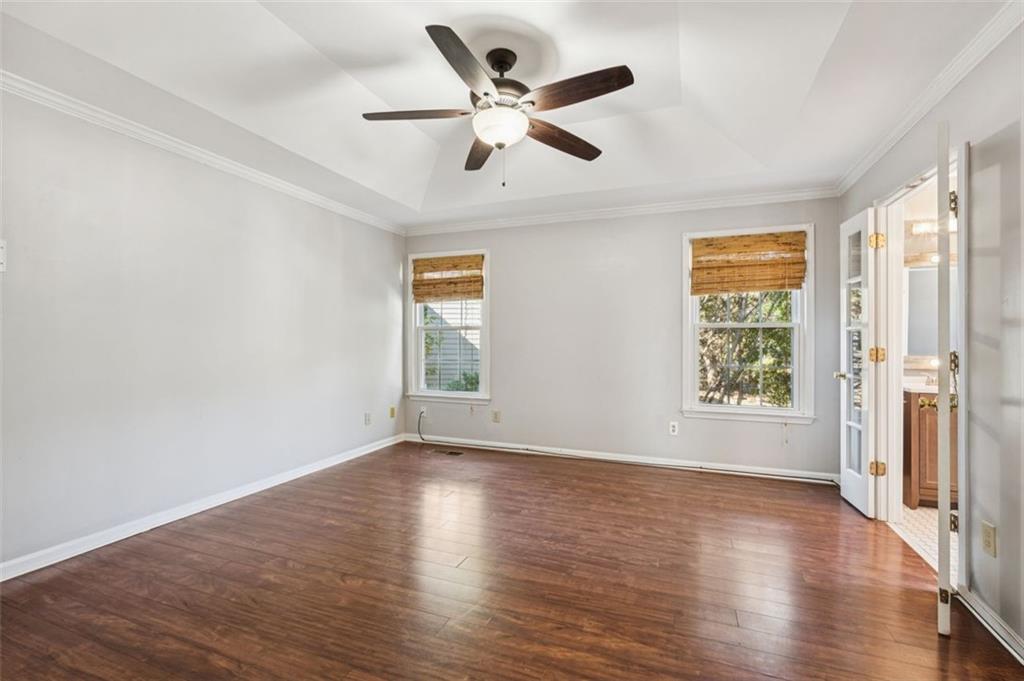 2470 Jakin Way Suwanee, GA 30024 - Photo 22 of 64 an empty room with wooden floor chandelier fan and windows