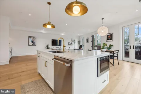 a kitchen with stainless steel appliances granite countertop a stove top oven a sink dishwasher and a dining table with wooden floor