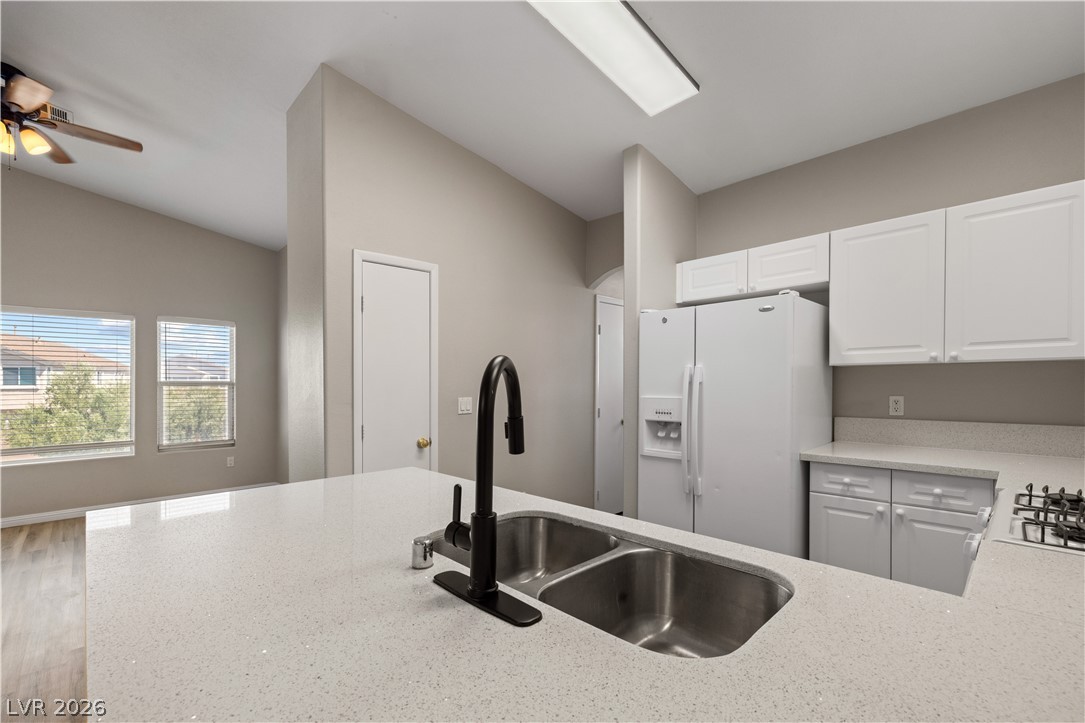 8777 Roping Rodeo Avenue, Unit 101 Las Vegas, NV 89178 - Photo 6 of 25 A well-appointed kitchen features a deep double sink with a modern faucet set into a luminous countertop.