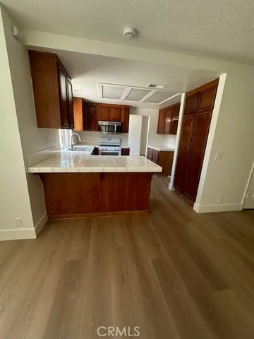 a view of kitchen with stainless steel appliances wooden floor and window