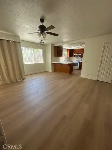 a view of a livingroom with wooden floor a ceiling fan and windows