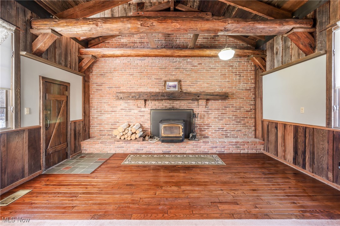 3210 Oser Road Norton, OH 44203 - Photo 23 of 47 Unfurnished living room featuring a wood stove, hardwood / wood-style floors, and wooden walls