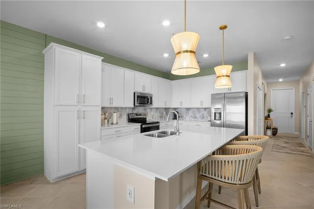 a kitchen with stainless steel appliances kitchen island granite countertop a sink a stove a refrigerator cabinets and chairs