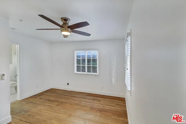 a view of empty room with wooden floor and ceiling fan