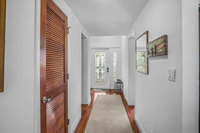 a view of a hallway with wooden floor and a bathroom