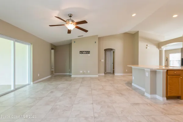 a view of a livingroom with a ceiling fan & kitchen space