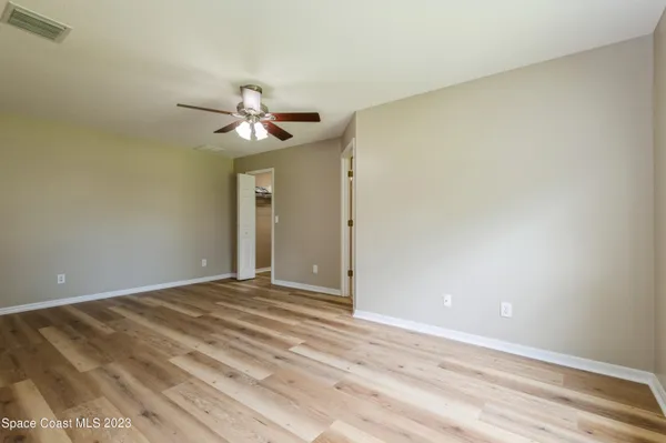 a view of an empty room and chandelier fan
