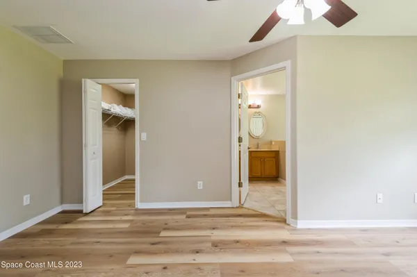 a view of a hallway with wooden floor and a bathroom