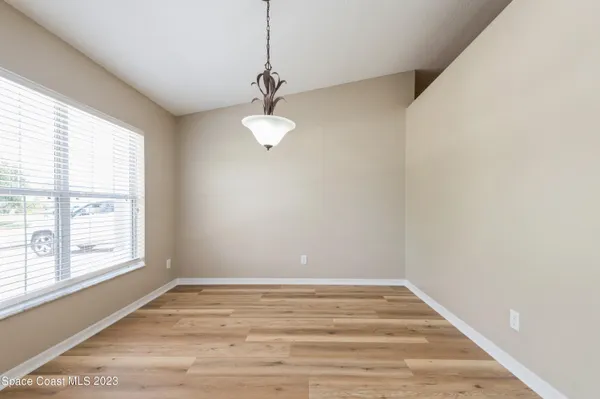 a view of empty room with window and wooden floor