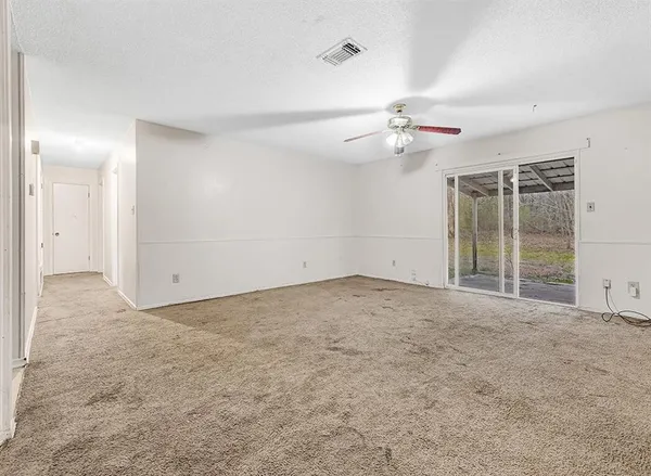 an empty room with chandelier fan and windows