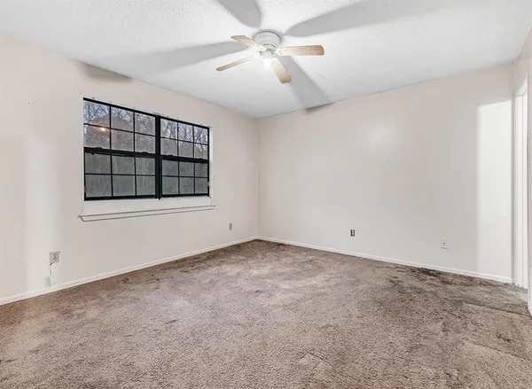 an empty room with windows and fan