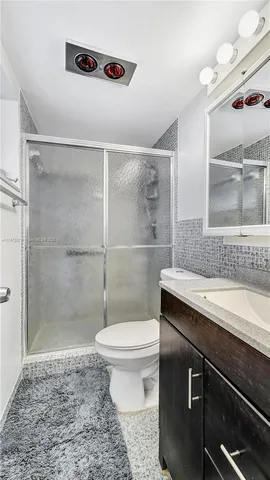 a bathroom with a granite countertop sink a toilet a mirror and shower