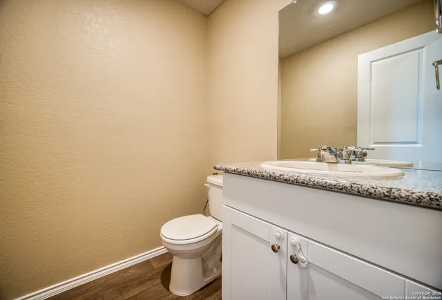 a bathroom with a granite countertop toilet and a sink
