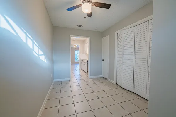 a view of an empty room and chandelier fan