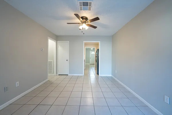 a view of an empty room with window and a chandelier fan