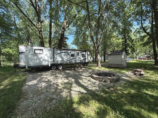 a view of a backyard with large trees and a barn