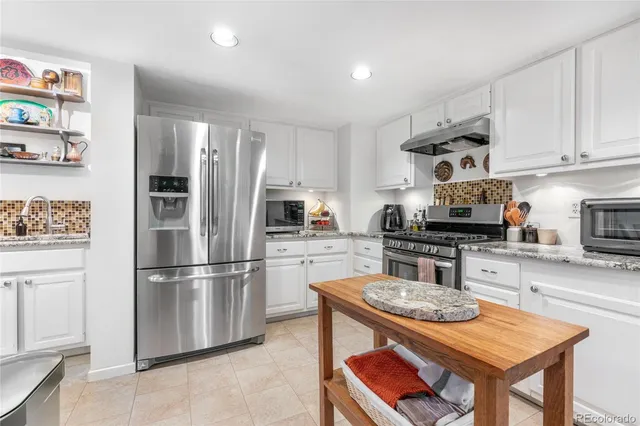 a kitchen with stainless steel appliances granite countertop a stove refrigerator sink and cabinets