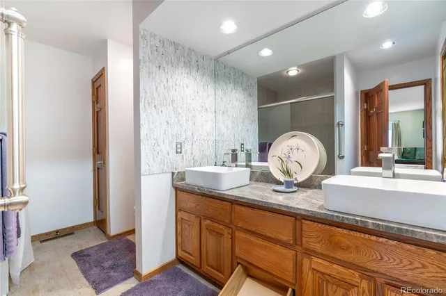a spacious bathroom with a granite countertop sink a mirror and shower