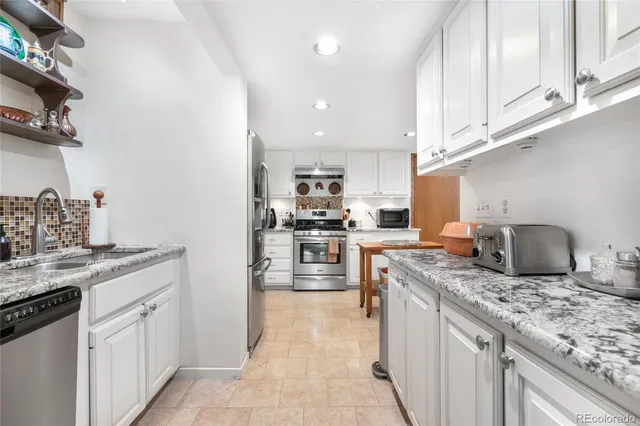 a kitchen with granite countertop kitchen island stainless steel appliances a sink stove top oven and cabinets